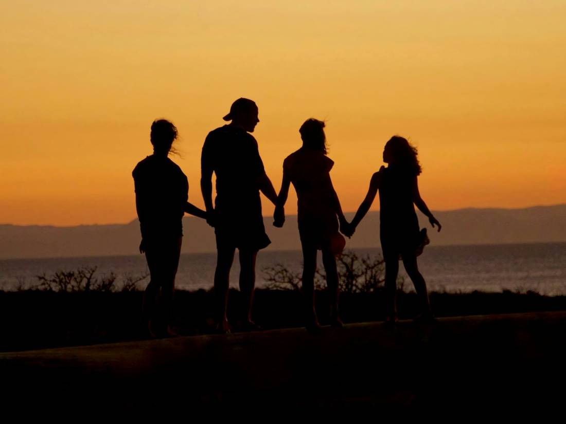 A family holding hands at sunset