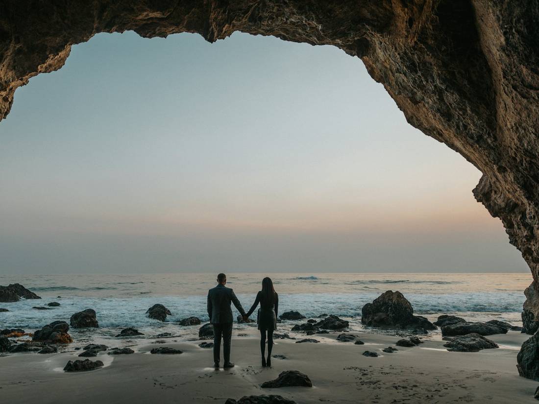 A couple holding hands, looking out at the sea